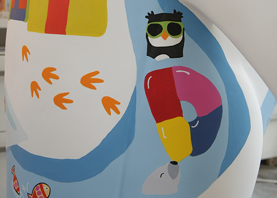 Playful grey seal balancing ball on its nose shaped as the letter D. Black and white penguin with green jumper. Colourful fish. Penguin with green glasses playing in the water